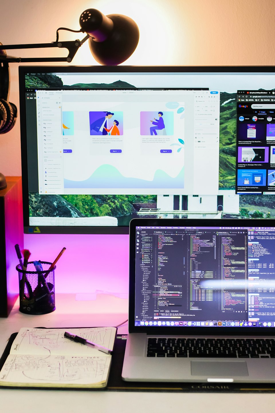 Un escritorio moderno con un monitor, portátil y cuaderno.