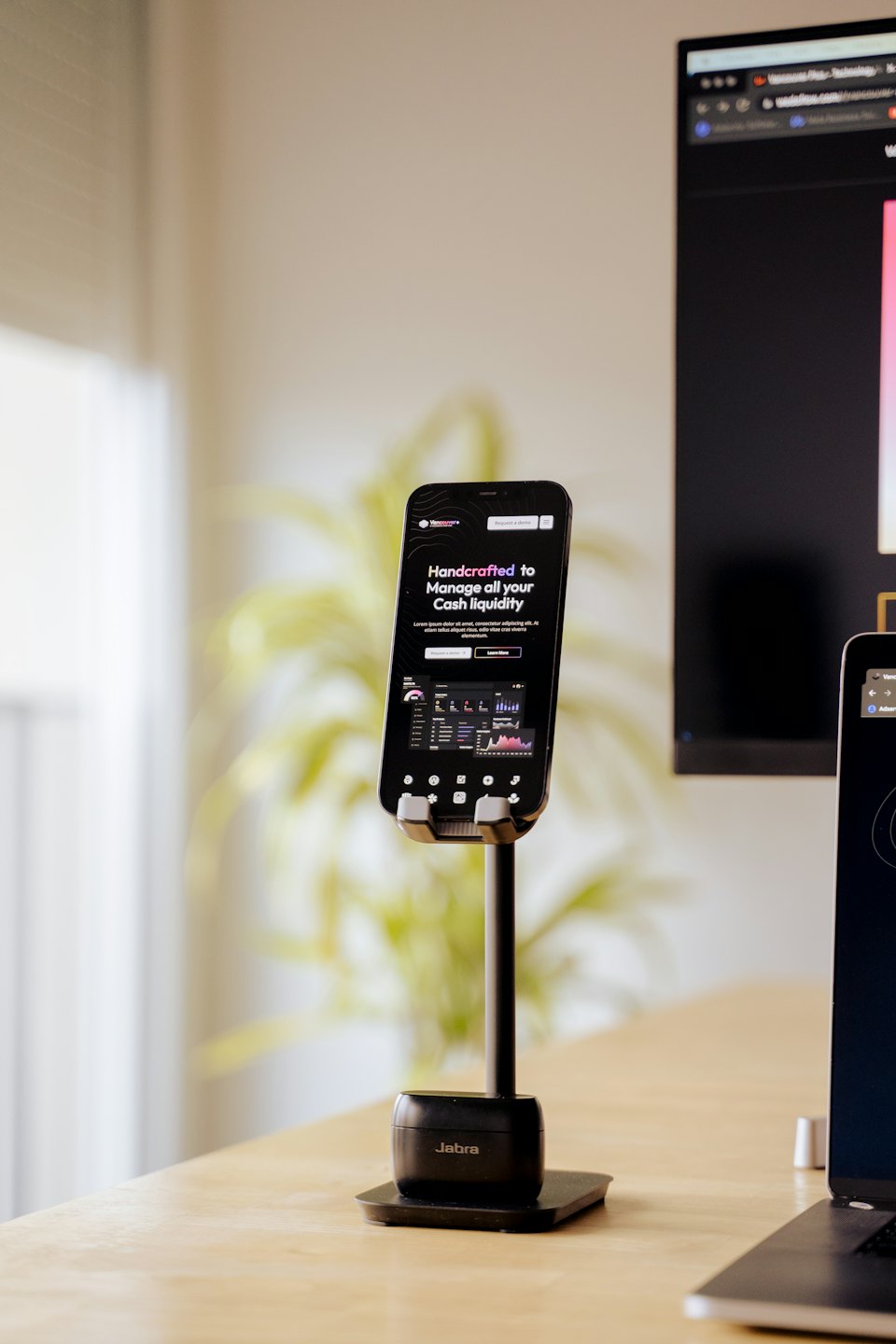 Smartphone en un soporte mostrando un panel de negocios sobre un escritorio.